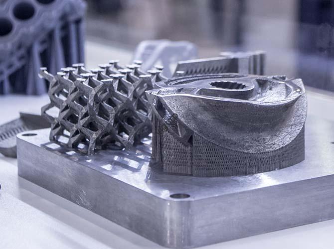 man is holding object printed on metal 3d printer.